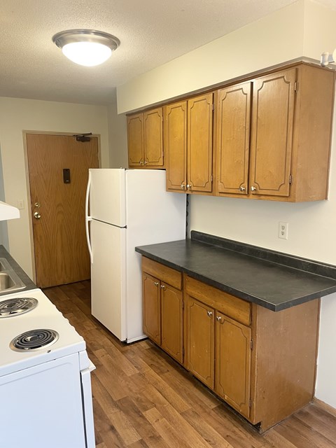 A kitchen with wooden cabinets and a white fridge.